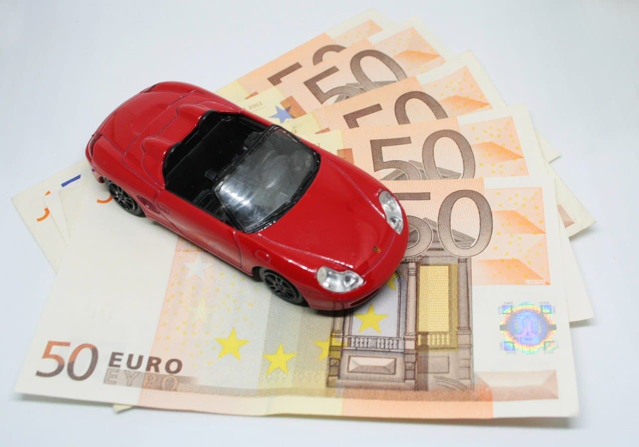 Une voiture miniature posée sur des billets de banque